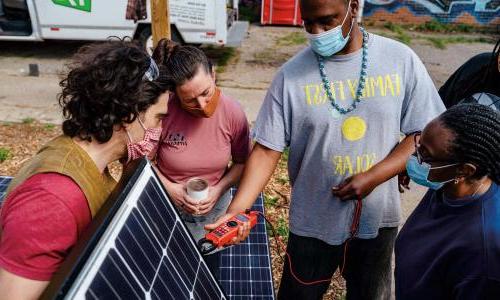 Highland Park community residents inspect a solar panel.
